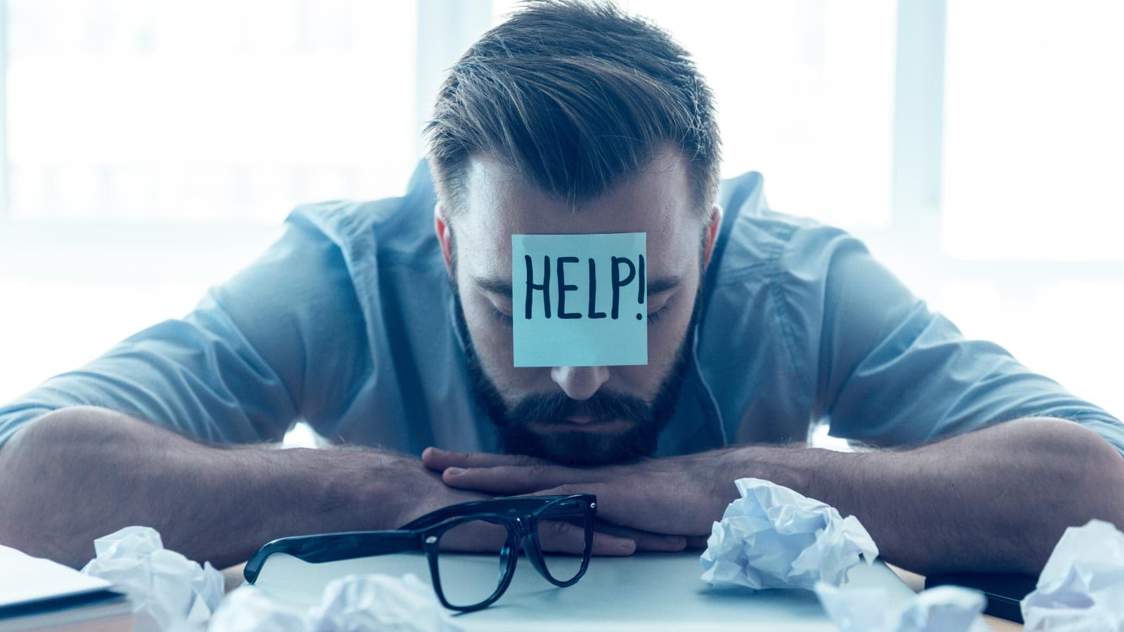 Sad man behind laptop with a help sticker on his face