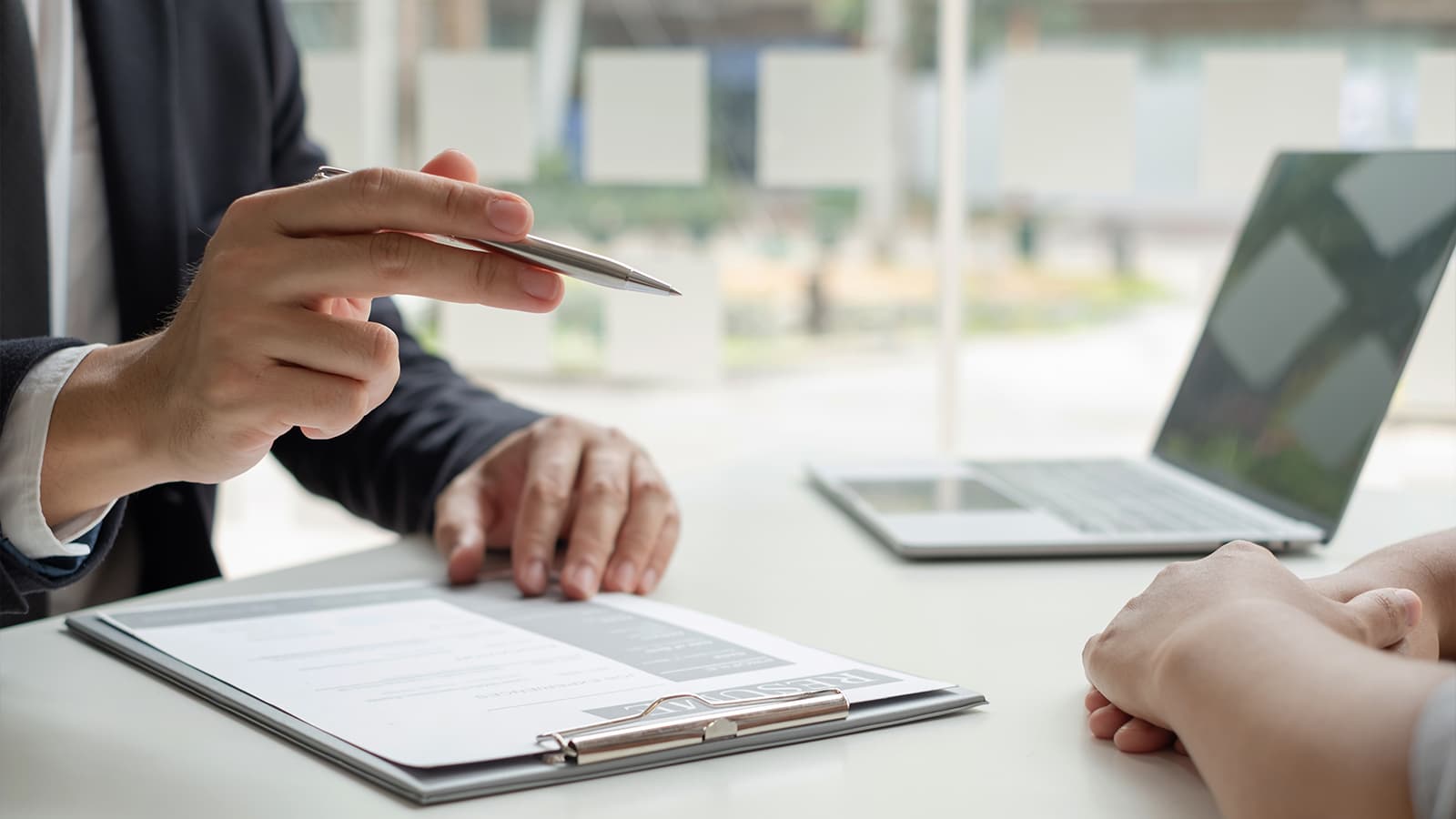 Hand holding pen over desk with resume