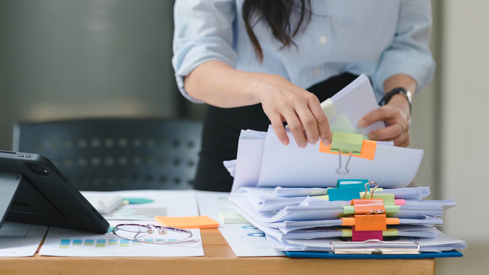 Hands on big pile of papers with bulldog clips