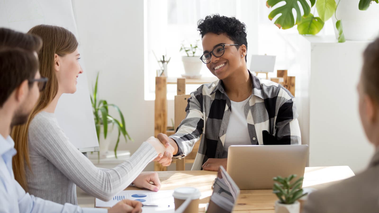 Two people shaking hands at an office table