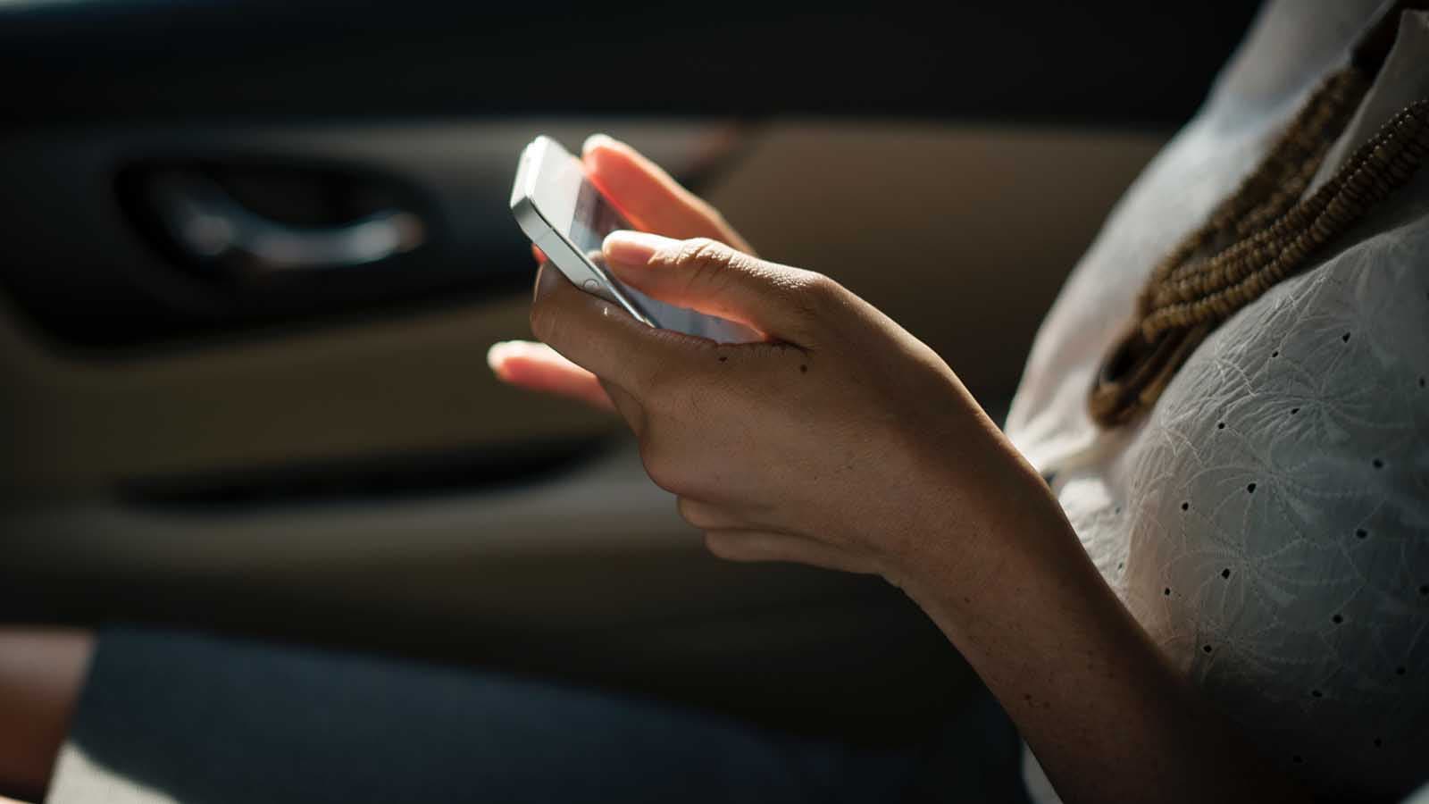 Person sitting on their phone in the car