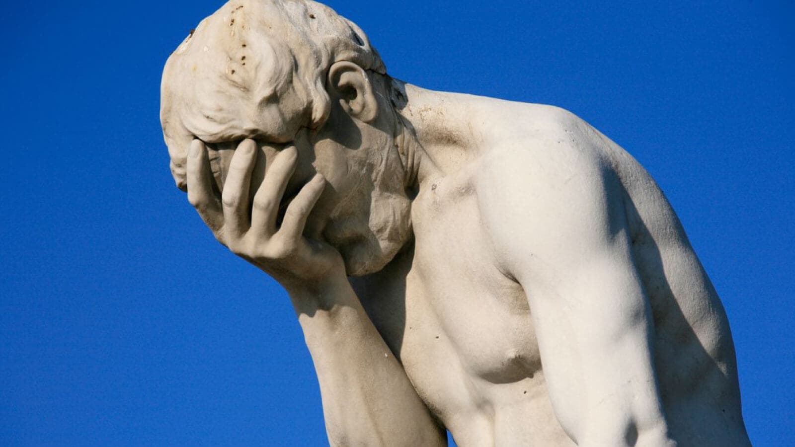 Statue holding his face