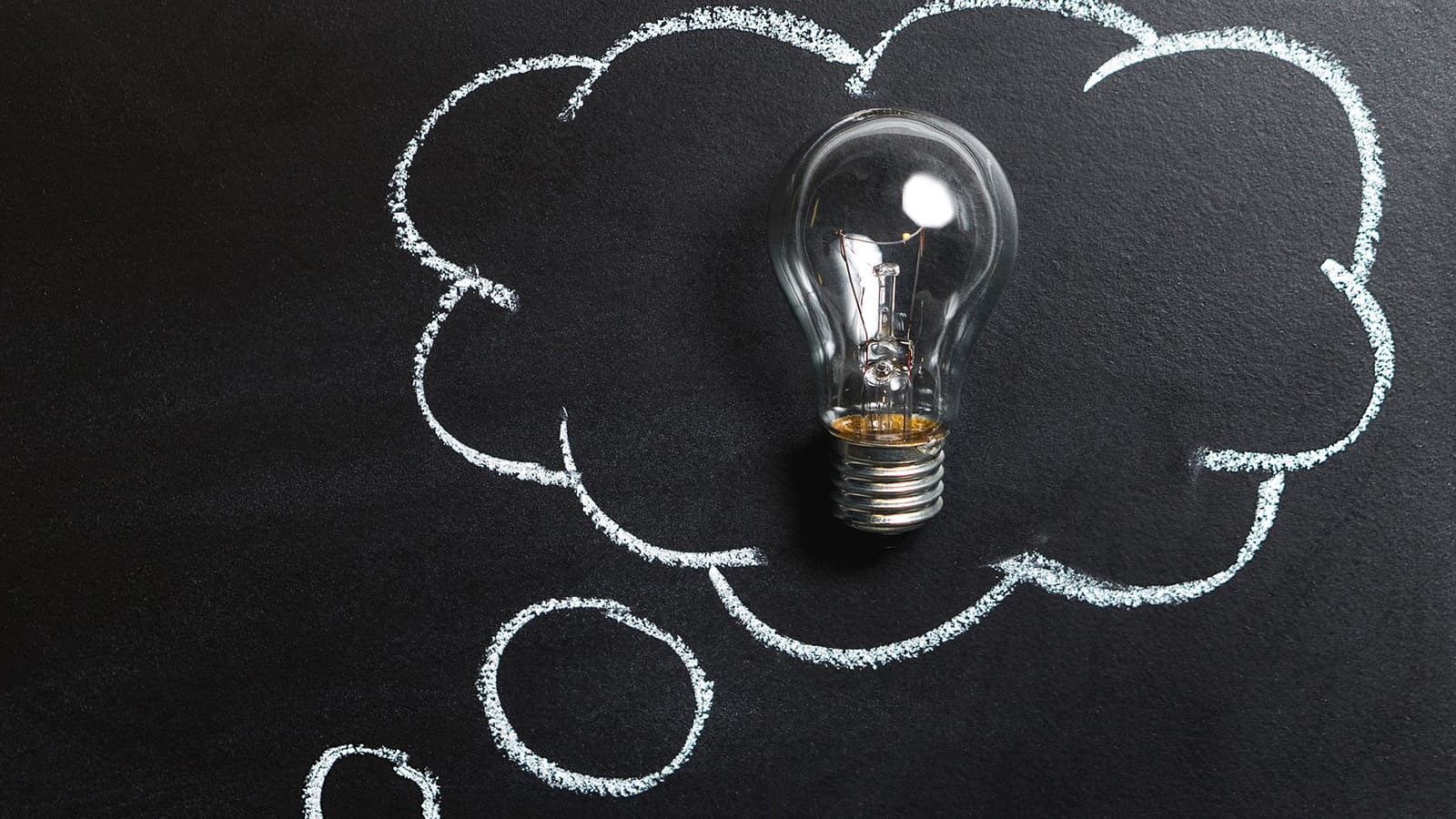 Lightbulb on a black background with a thought bubble drawn around it