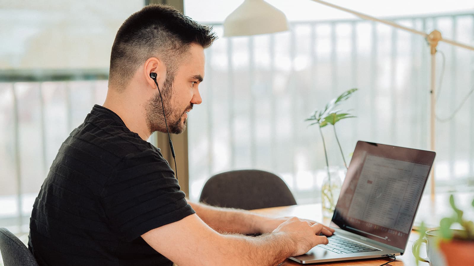 Man in black t-shirt wearing earphones and typing