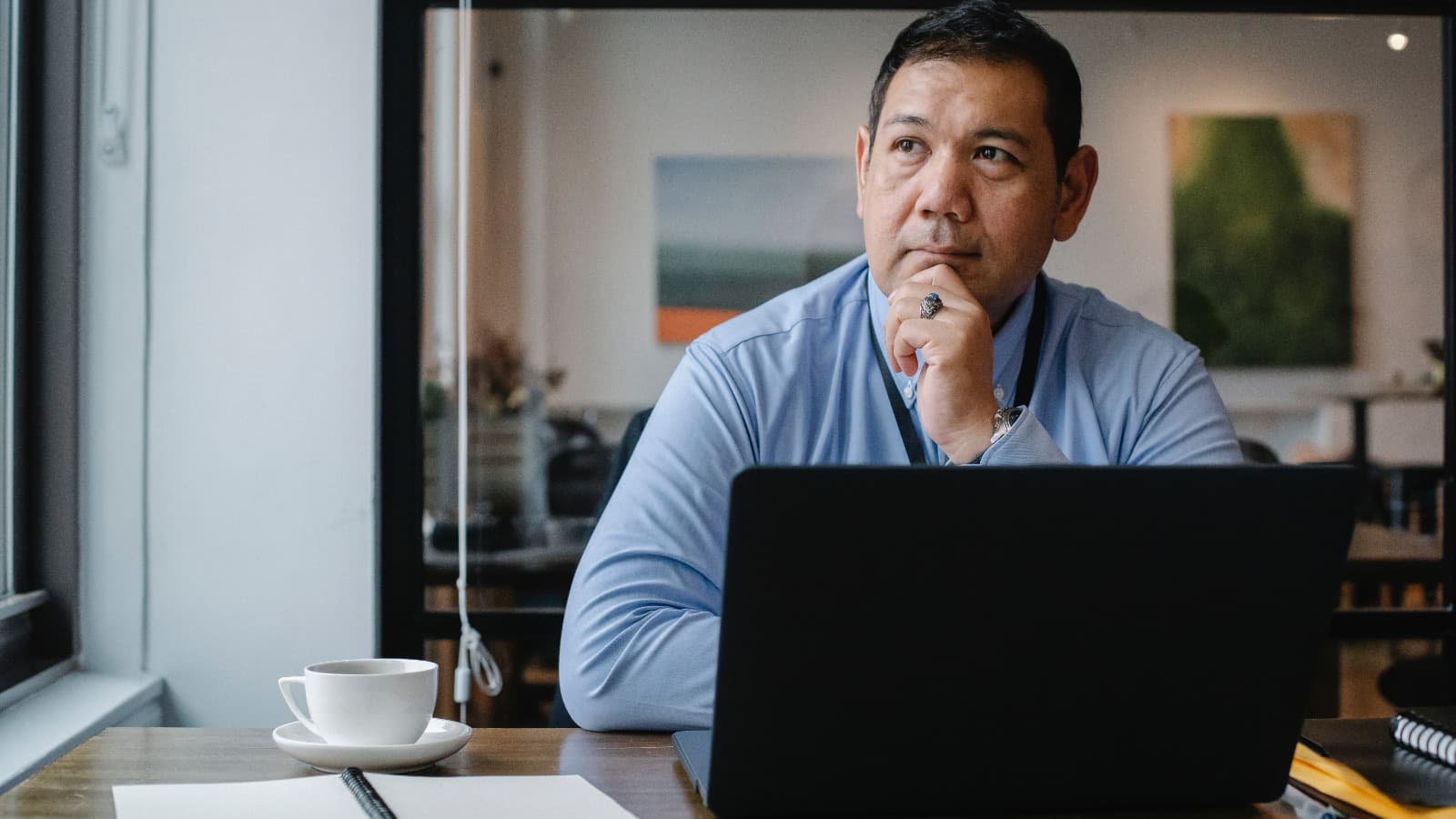 Man in front of laptop looking thoughtful