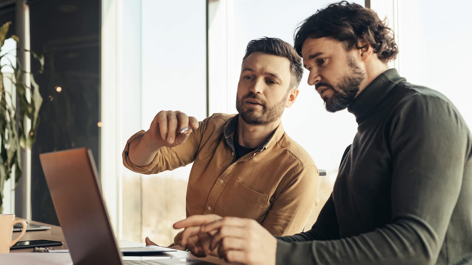 Two men looking at laptop, one pointing at screen