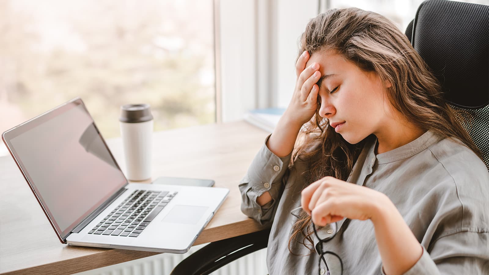 Burnt out woman at computer with hand on face