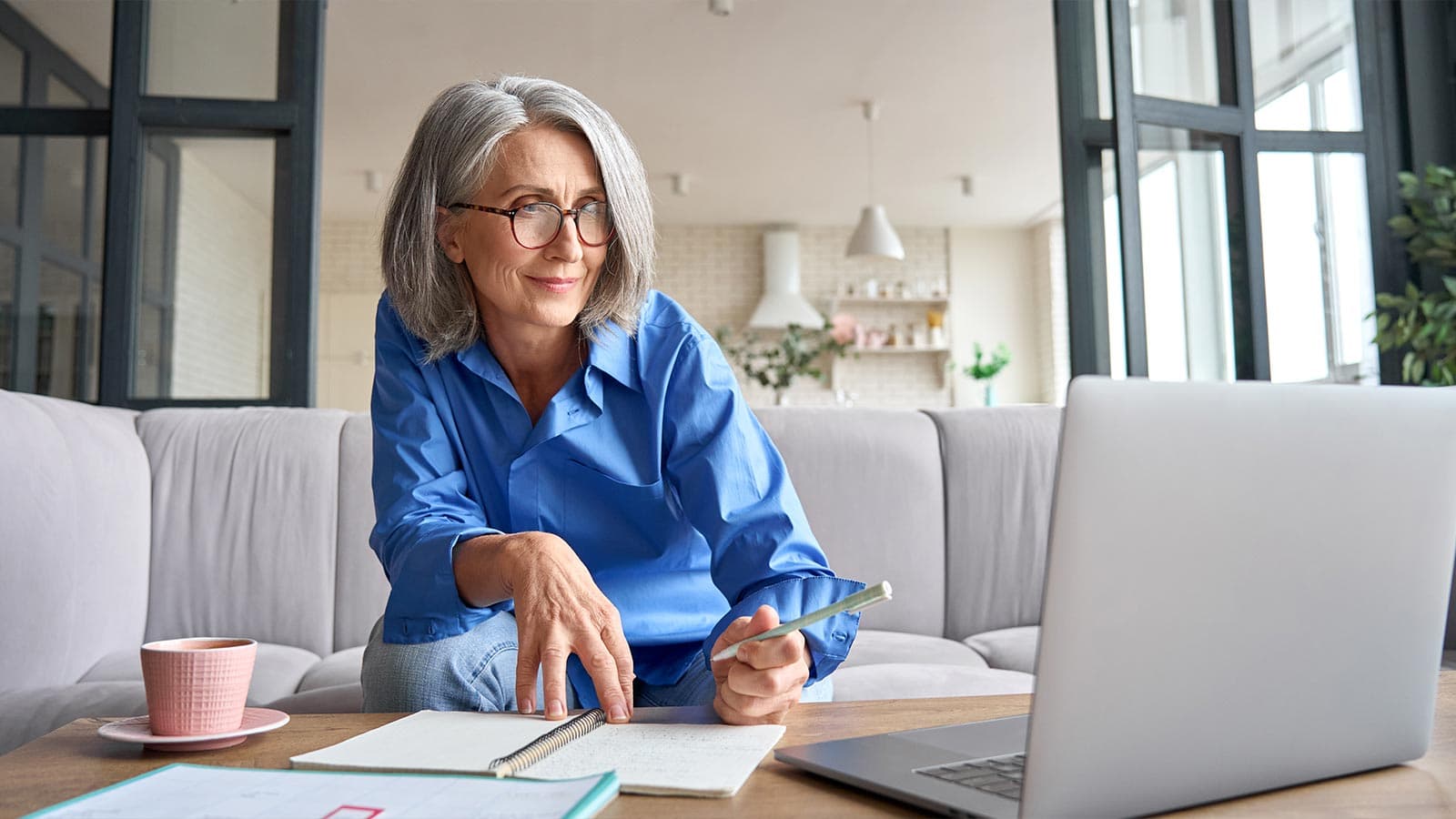 Woman looking at laptop while writing notes