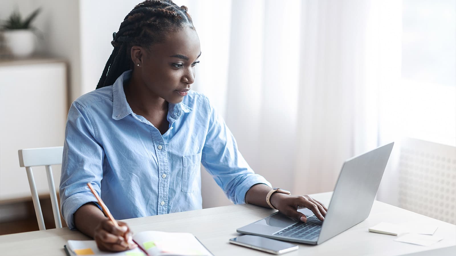 Woman sitting in front of laptop writing notes