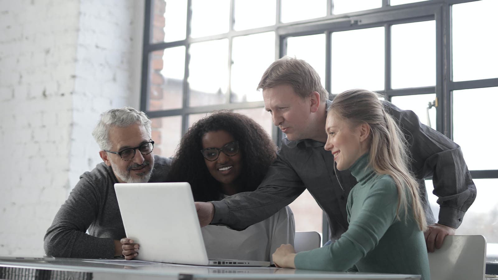 Four people squeezed around a laptop