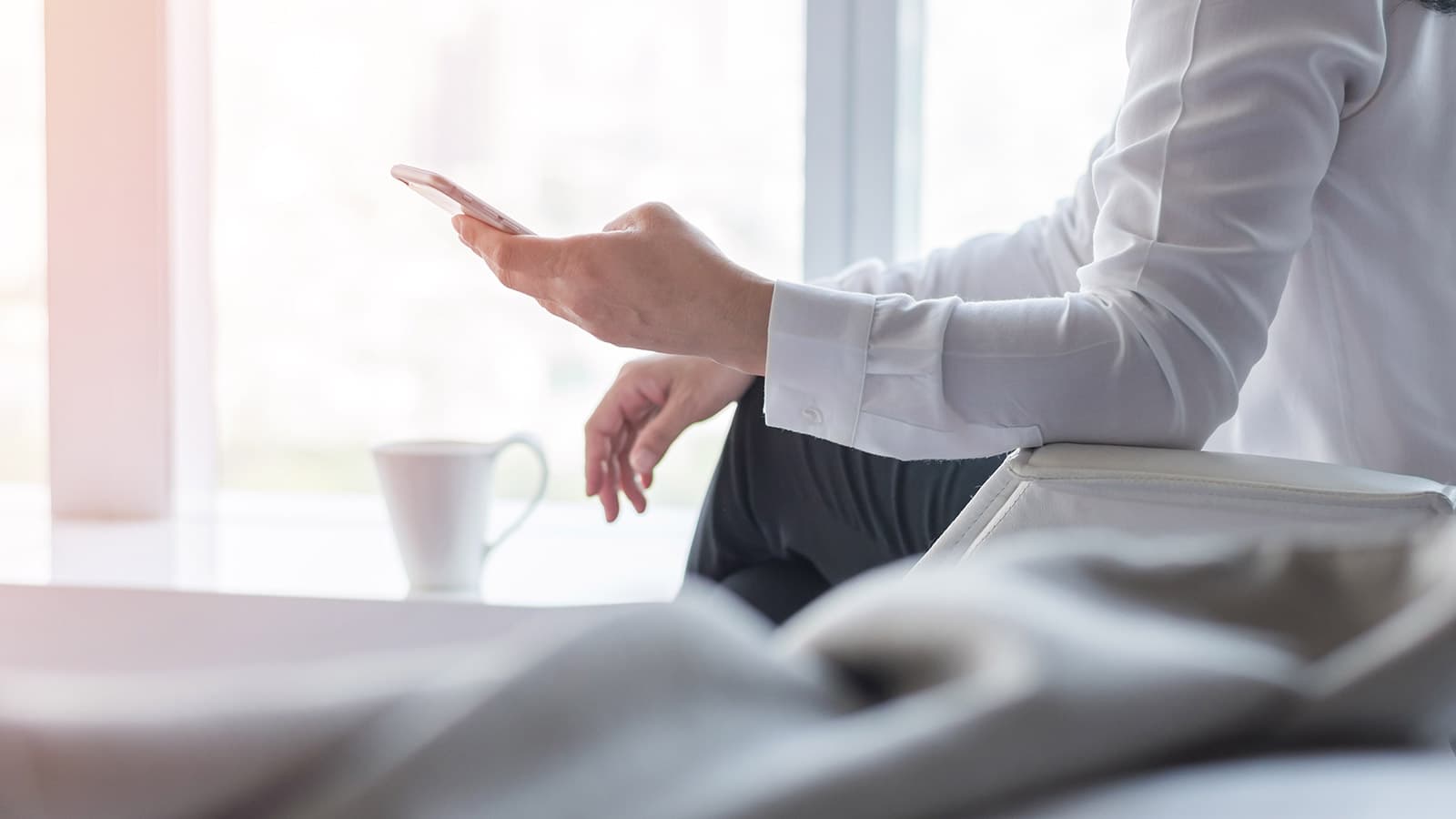 Arm in white shirt with hand holding cell phone