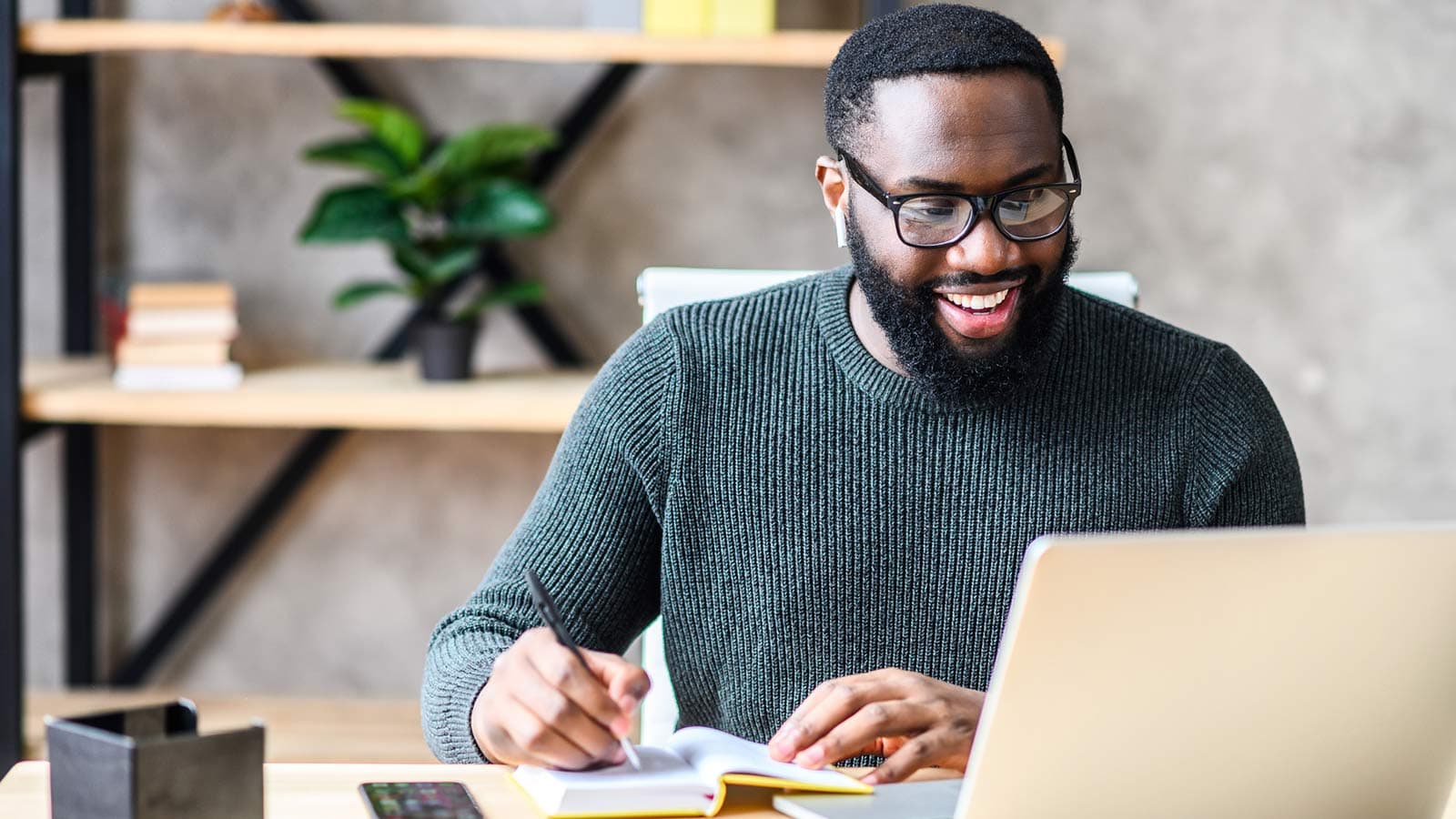 Man grinning at laptop as he writes