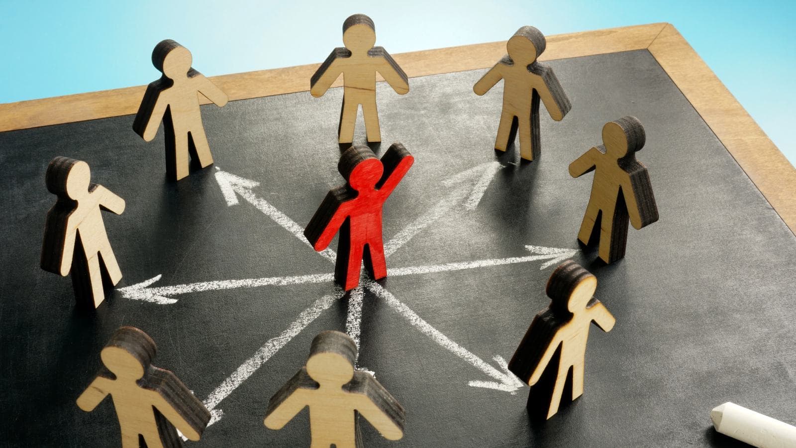 8 wooden men standing in circle, red man in middle