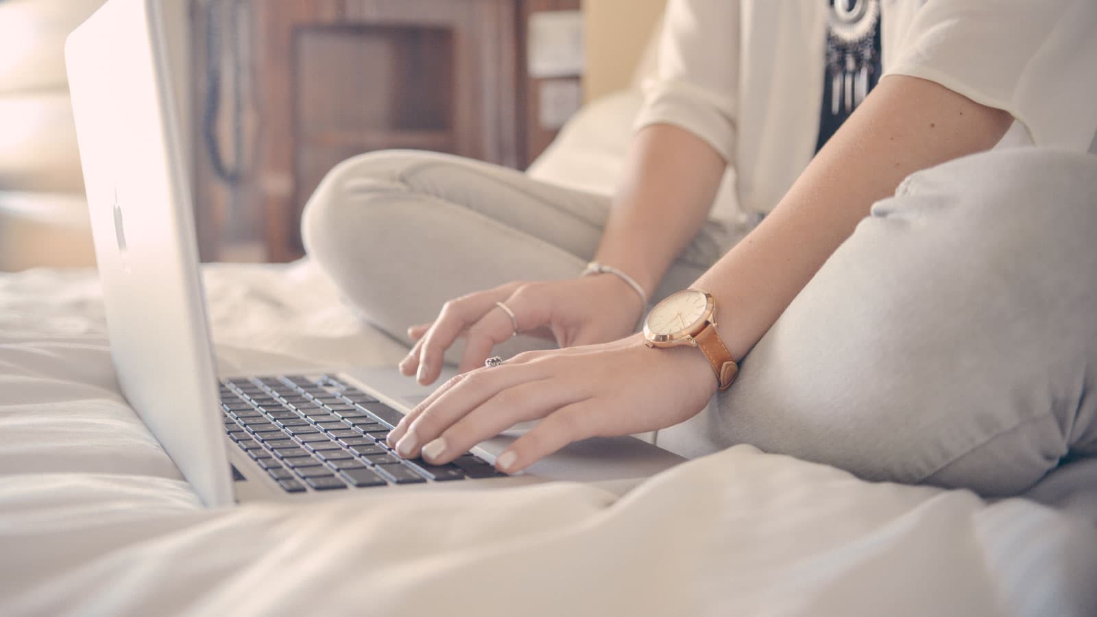 Woman sitting on be typing on computer