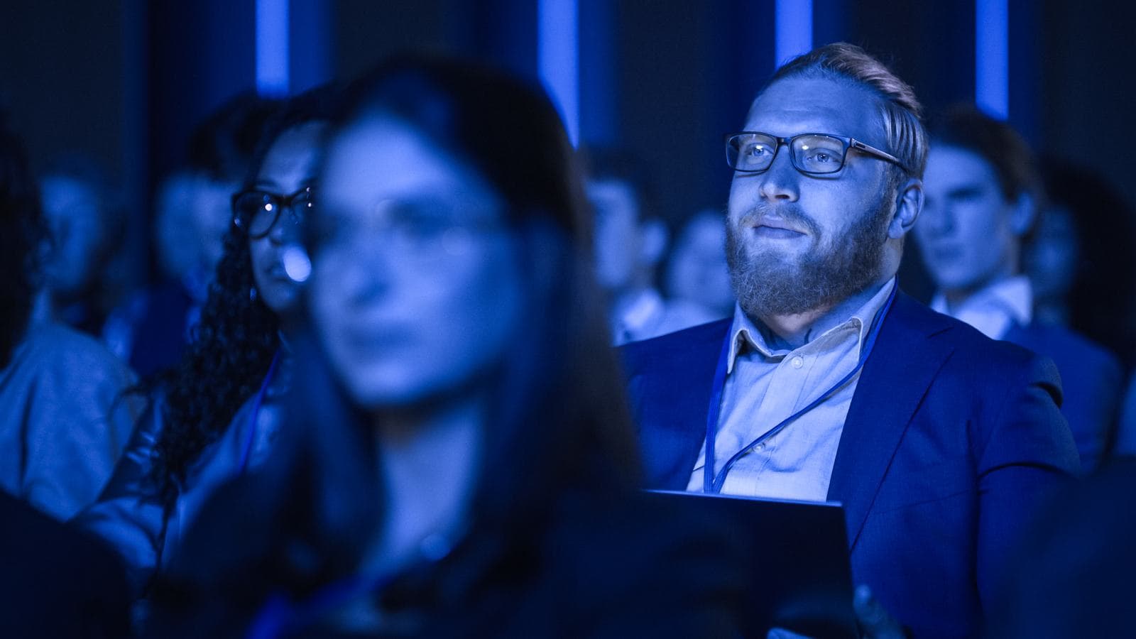 Tightly packed audience bathed in blue light