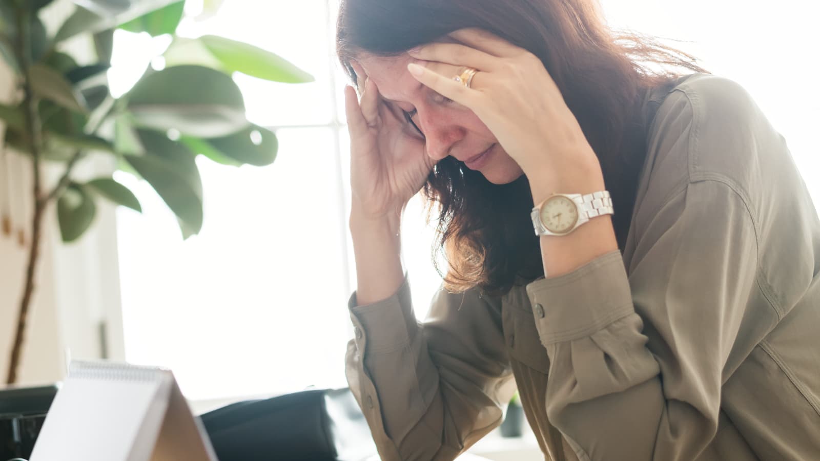 Woman at a desk with head in hands