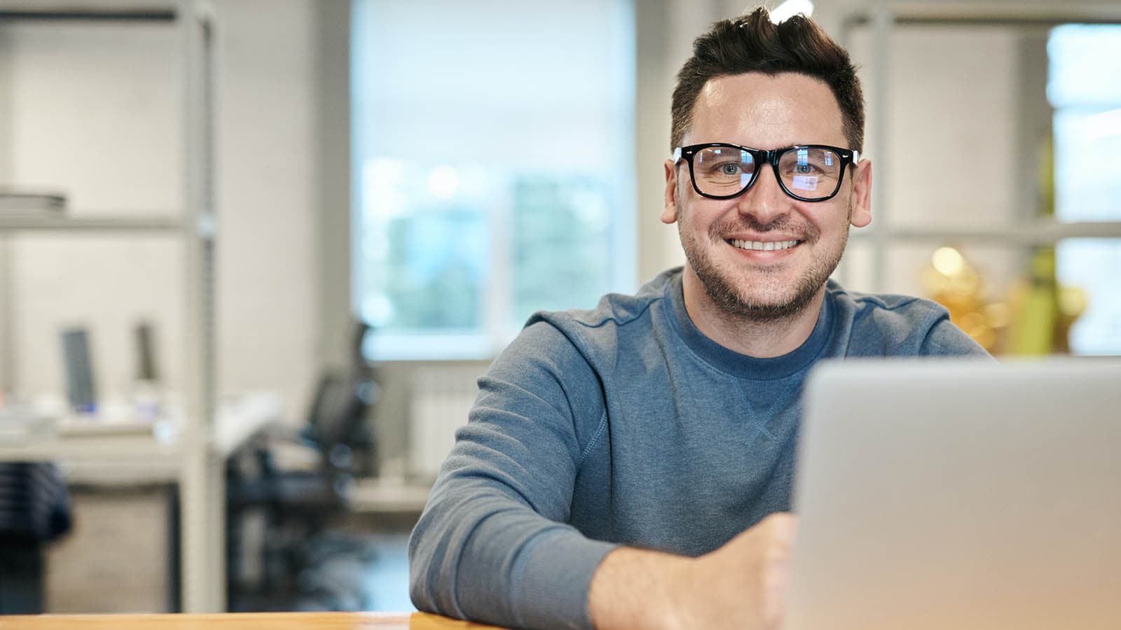 Man smiling from behand a laptop