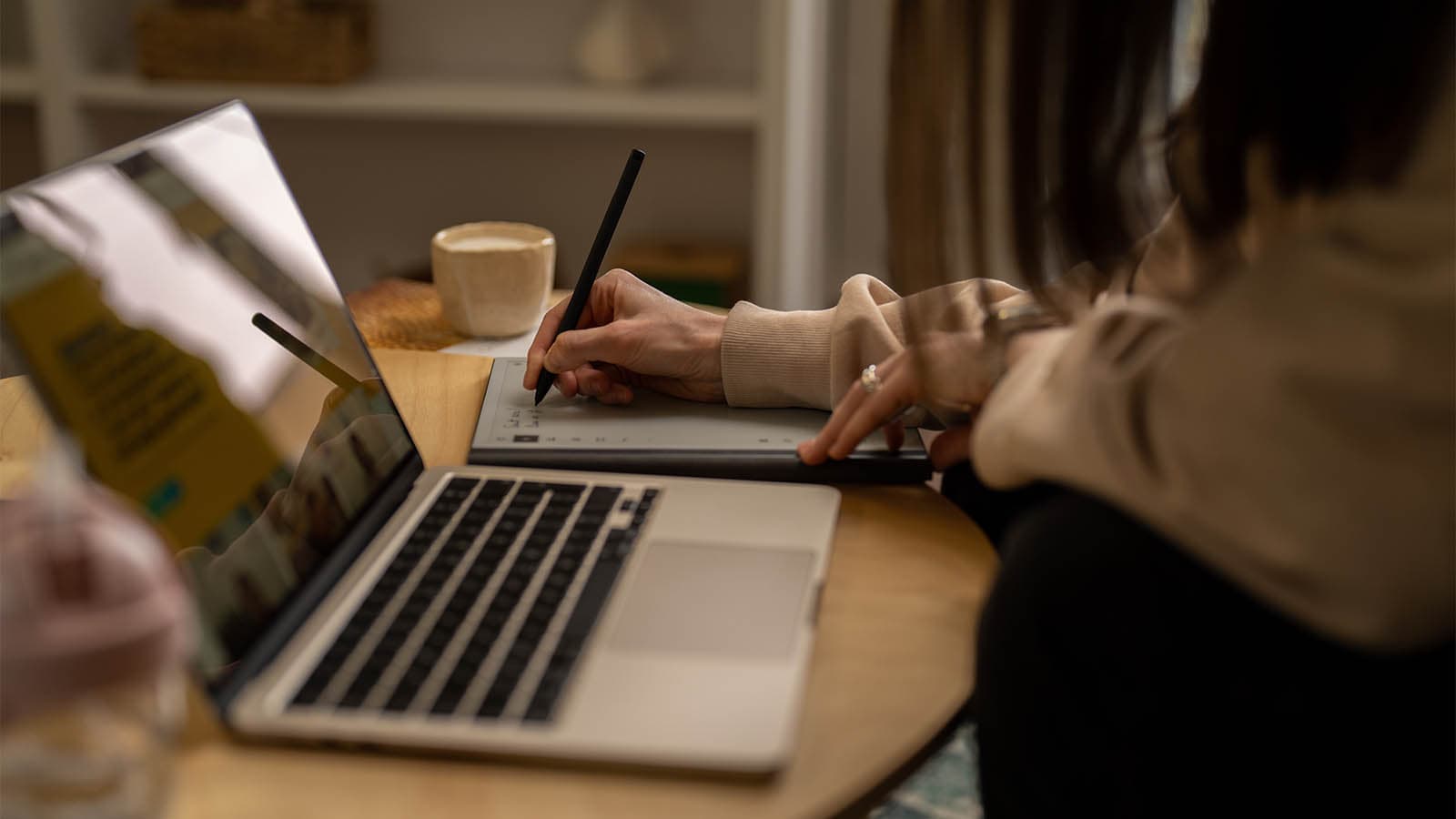 Laptop on round table, hand writing on notepad